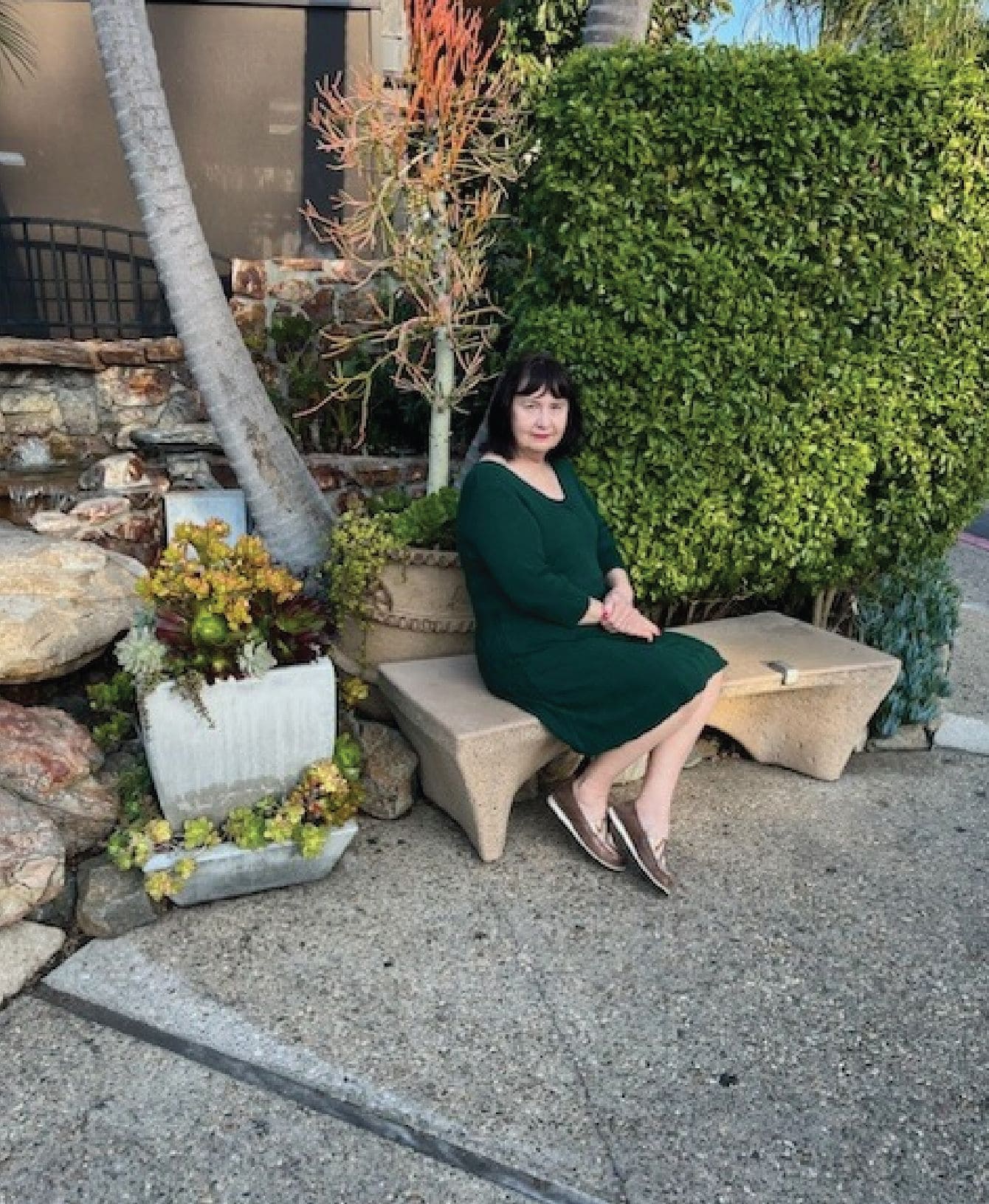  A woman in a green dress sitting on a bench in a park